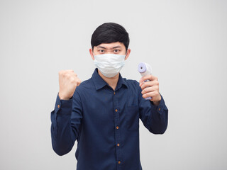 Portrait asian man wearing mask show fist up and holding infrared thermometer in hand white...