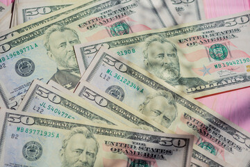 Closeup American cash banknotes. Dollars on a pink wooden background. Finance concept.