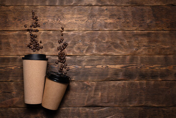 Two coffee mugs and roasted coffee beans on the wooden table flat lay background with copy space.
