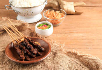 Selected Focus Homemade Indonesian Lamb Satay (Sate Kambing) is Popular Menu for Idul Adha (Eid al Adha), Copy Space. Served with Rice Cake (ketupat) or Lontong