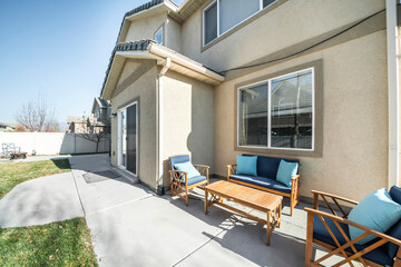 Patio outside a two-storey house with concrete flooring and green lawn