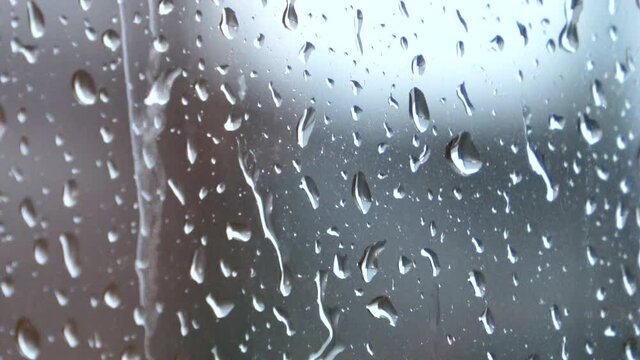 ガラスの表面を流れ落ちる水滴  雨の雫のクローズアップ  4K