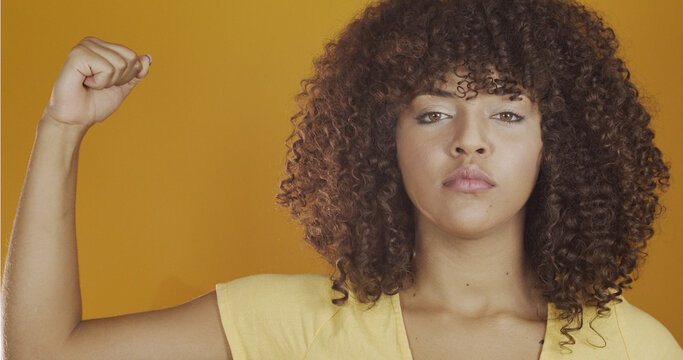 We can do it. Woman's fist of female power. Woman victim of racism. Abuse at work. The feminine power. Female empowerment. The strength of women. Yellow background