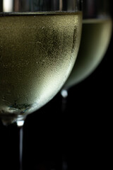 macro photo of two glasses of white wine. Two glasses with chilled wine in it and condensation and drops on them