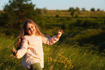  Happy cute funny smiling dancing and singing caucasian girl walking on the meadow. Summer sunset.  Happy Childhood concept. Nature background. Copy space