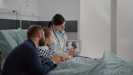 Pediatric cardiologist woman doctor explaining heart illness using tablet with medical cardiogram...