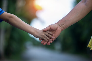Parents holding little children's hands at sunset