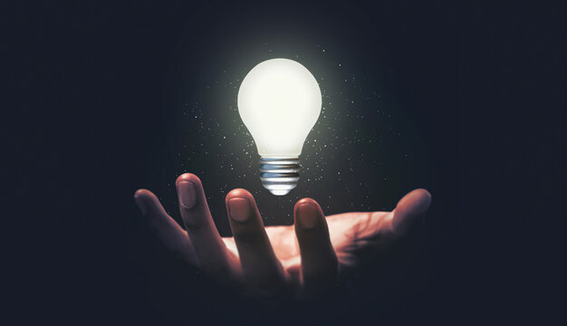 Hand hold glowing idea light bulb and innovation thinking creative concept on success inspiration dark background with solution creative business design.