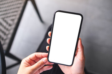 Top view mockup image of a woman holding mobile phone with blank white desktop screen