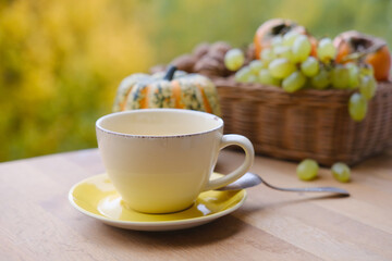 pumpkin, fruits on the table in the garden, beautiful blurred natural landscape, a cup of hot tea, coffee, seasonal concept, cozy autumn mood
