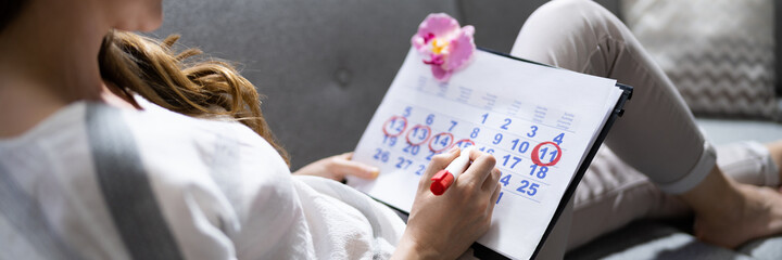 Woman Filling Period In Menstruation Calendar