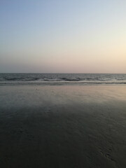Vertical shot of a beautiful beach with low tides coming from the sea under a gradient sky