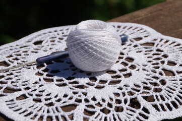 knitted napkin and a ball of thread with a crochet hook