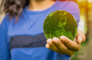 smiling woman holding planet in hands against green spring background. Earth day concept. earth in hands. save of earth.World environment day and sustainable environment concept.
