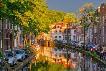 Delt canal with old houses and cars parked along on sunset