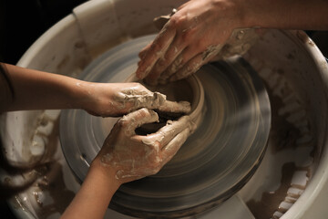 the child is engaged in pottery with a teacher. teaching schoolchildren. hobbies and leisure for children. clay modeling on a potter's wheel