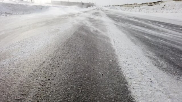 Wind blowing snow over the road. snowdrift close up. winter blizzard