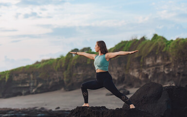 Naklejka na ściany i meble Girl doing yoga by the sea.