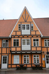 Historic and typical orange and wooden painted timbered building with white windows and doors in the city center, Aalborg, Denmark.