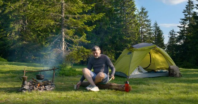 The man drinks tea and looks at the map in the Camping.