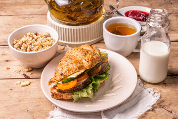 Healthy breakfast concept. Morning good mood with tea, croissant, granola, milk, and jam