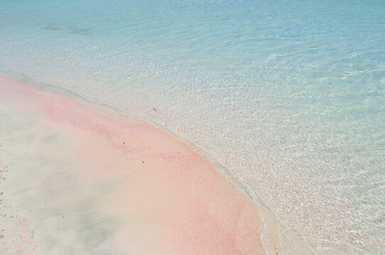 Pink paradise sandy beach with blue water.