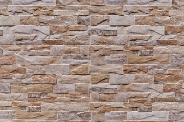 Patterned wall tiles as split natural stone background. Simulated brown natural stone facade, wall tiles texture.