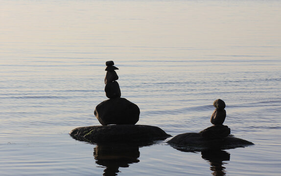 Stones in the water are stacked in pyramids. Image on the topic of balance and peace of mind