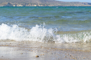 Close-up sea wave with white foam on a sandy tropical beach.
