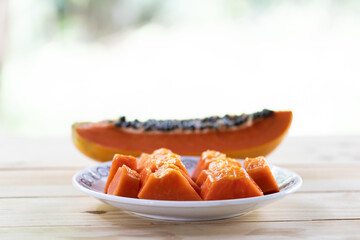 Ripe papaya is cut into pieces in plate on wooden table