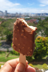 Hand holding ice cream with bokeh outdoor background.