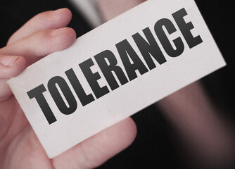 Tolerance words on a card in businessman hand. Social concept against discrimination at workplace