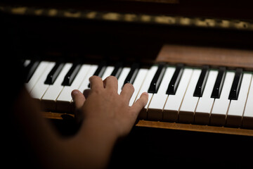 Spotlight on keys of a piano with a single hand playing in moody atmospheric light. Music still...
