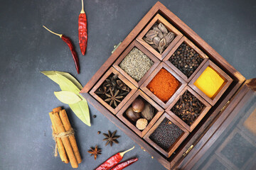Variety of Indian spices and herbs in a wooden box. Multicolored spices in a wooden organizer, top...