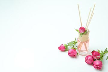 Diffuser and pink roses on white background