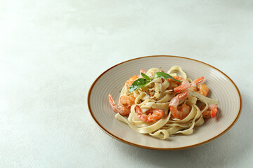 Plate of shrimp pasta on white textured background