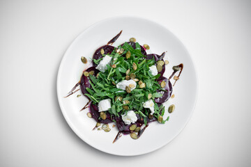 top view of salad with beet, arugula or feta cheese on plate on white background