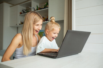 surprised mom and daughter sit at laptop at home 