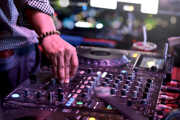 DJ hand playing live set and mixing music on controller turntable console mixing desk at stage in...