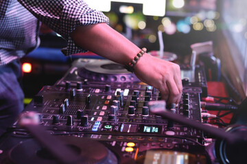 Fototapeta na wymiar DJ hand playing live set and mixing music on controller turntable console mixing desk at stage in the night club, music beach party festiva and nightlife