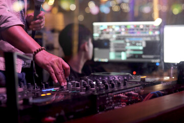 DJ hand playing live set and mixing music on controller turntable console mixing desk at stage in...