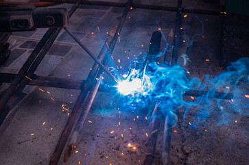 Close-up worker electric welding steel to connect the seam of metal partใ Blue fire flickers, orange sparks are flying