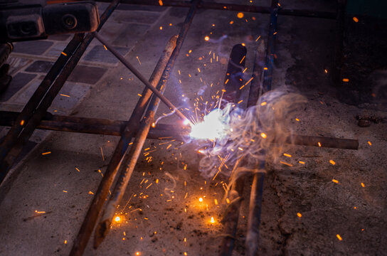 Close-up worker electric welding steel to connect the seam of metal partใ Blue fire flickers, orange sparks are flying