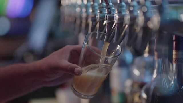 Male Hand Filling A Glass With Beer From The Tap At The Casino. close up