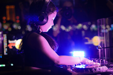 Little girl DJ playing live set and mixing music on controller turntable console mixing desk at...