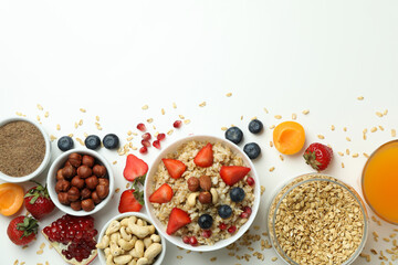 Bowl of oatmeal and ingredients for cooking on white background