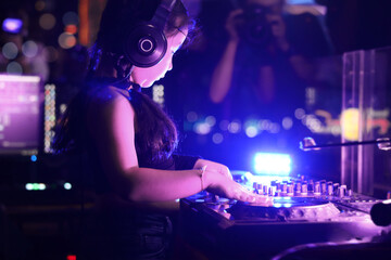 Little girl DJ playing live set and mixing music on controller turntable console mixing desk at stage in the night club, music beach party festiva and nightlife concept.