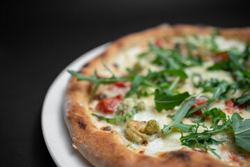 closeup of seafood pizza with shrimp, mussels and arugula on black background