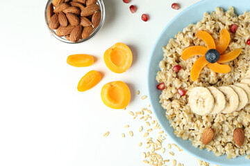 Bowl of oatmeal and ingredients on white background