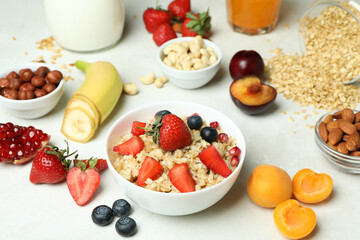 Bowl of oatmeal and ingredients for cooking on white background